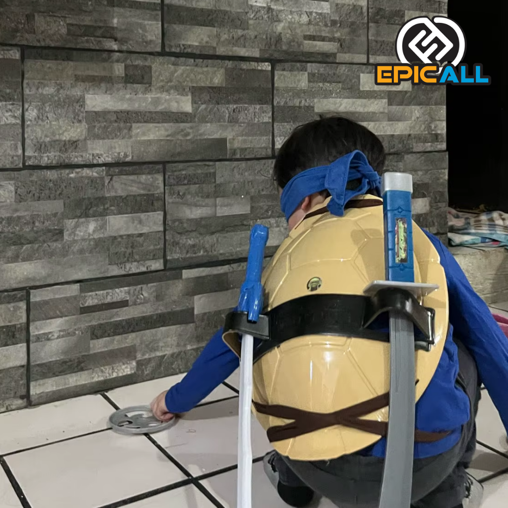 Un niño disfrazado con el caparazón de tortuga marrón, una máscara azul  , una espada y dos nunchakus.