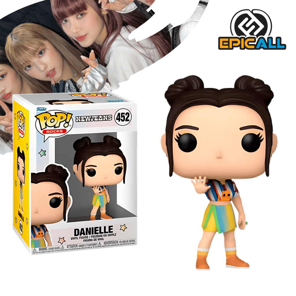 Un Funko POP de Danielle de NewJeans. La figura tiene el pelo largo y ondulado con un flequillo, un top corto blanco con un diseño, y pantalones de mezclilla o vaqueros. Tiene una expresión dulce y los ojos grandes y redondos, característicos de los Funko POP. La caja del Funko POP se ve detrás de la figura.