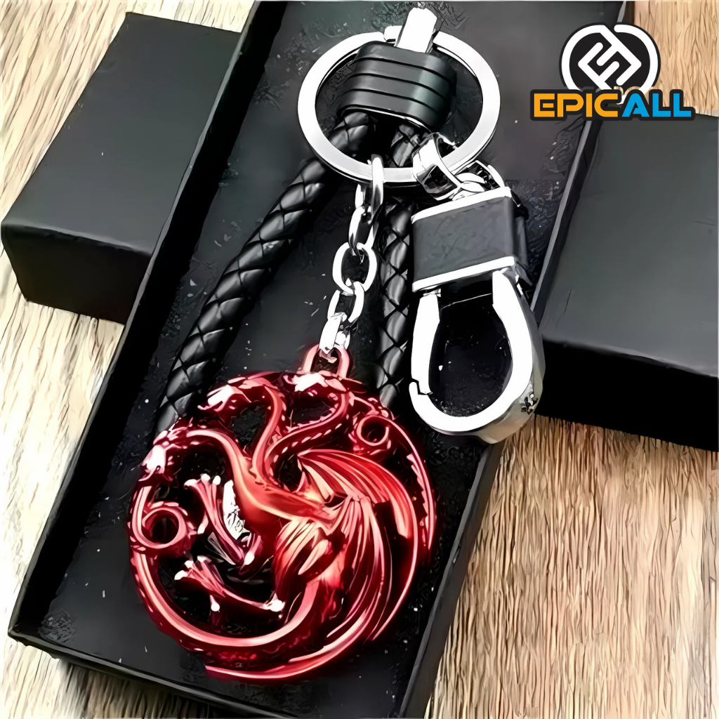 Un llavero con el emblema de la Casa Targaryen de Game of Thrones. El emblema representa tres dragones rojos rodeados de un círculo. El llavero tiene un cordón de cuero negro y un gancho metálico para las llaves.