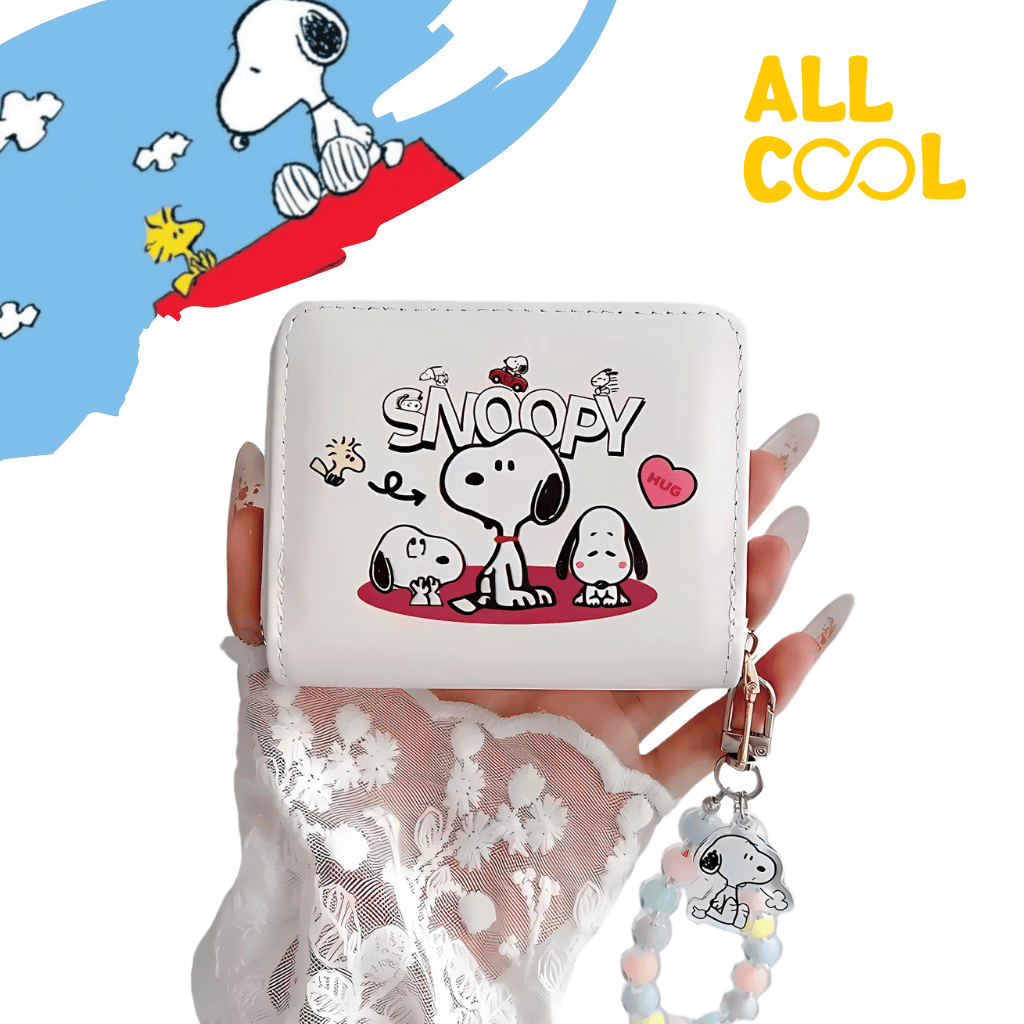 Billetera blanca con diseño de Snoopy y sus amigos. La billetera tiene corazones y está decorada con un llavero de Snoopy.