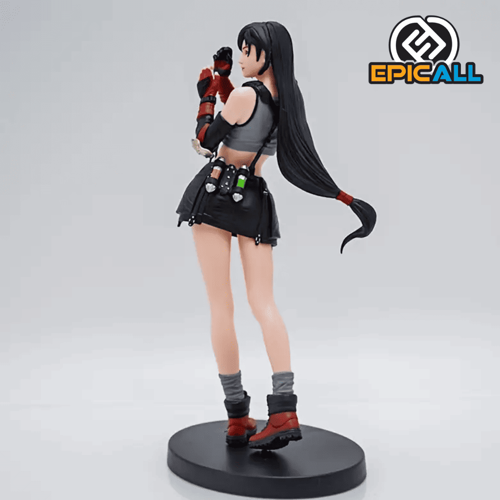 Una figura de acción de Tifa Lockhart, un personaje del videojuego Final Fantasy VII. Tifa está representada con su cabello negro, un vestido azul y guantes. Está en una pose de combate, con un puño levantado. La figura está colocada sobre una base que representa un entorno urbano.
