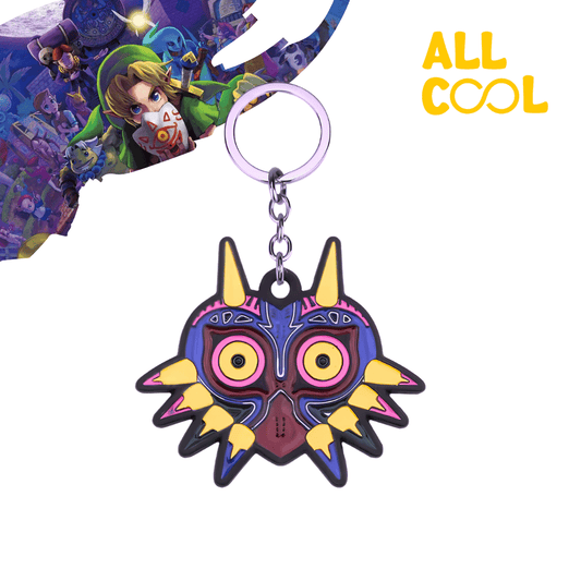 Un llavero metálico con la forma de la Máscara de Majora, un objeto mágico del videojuego The Legend of Zelda: Majora's Mask. La máscara tiene un diseño detallado con colores brillantes y está representada en tres dimensiones. El llavero mide 10 cm de largo aproximadamente.