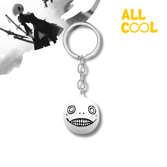 Llavero metálico con el diseño de Robot Face del videojuego Nier Automata. El llavero es de color plata y blanco.