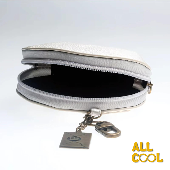 La imagen muestra un monedero blanco con detalles en relieve, diseñado como la cara de la lechuza Hedwig de Harry Potter. El monedero mide 13 cm de ancho y 11 cm de alto, y tiene un cierre en la parte superior, con un llavero y una etiqueta adicional.