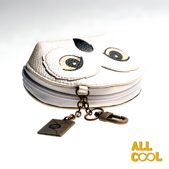 La imagen muestra un monedero blanco con detalles en relieve, diseñado como la cara de la lechuza Hedwig de Harry Potter. El monedero mide 13 cm de ancho y 11 cm de alto, y tiene un cierre en la parte superior, con un llavero y una etiqueta adicional.