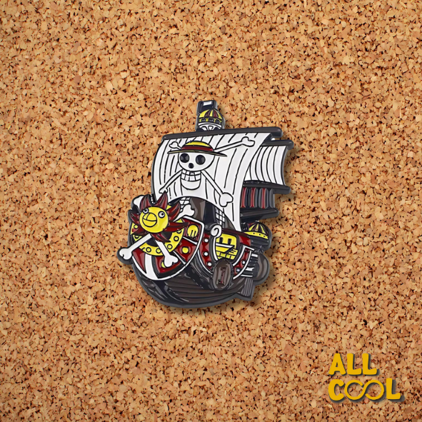 Un pin metálico con forma de barco pirata. El barco tiene un fondo rojo y velas blancas con un cráneo y huesos cruzados. En la parte inferior del barco hay una cara sonriente amarilla con dos huesos cruzados debajo.