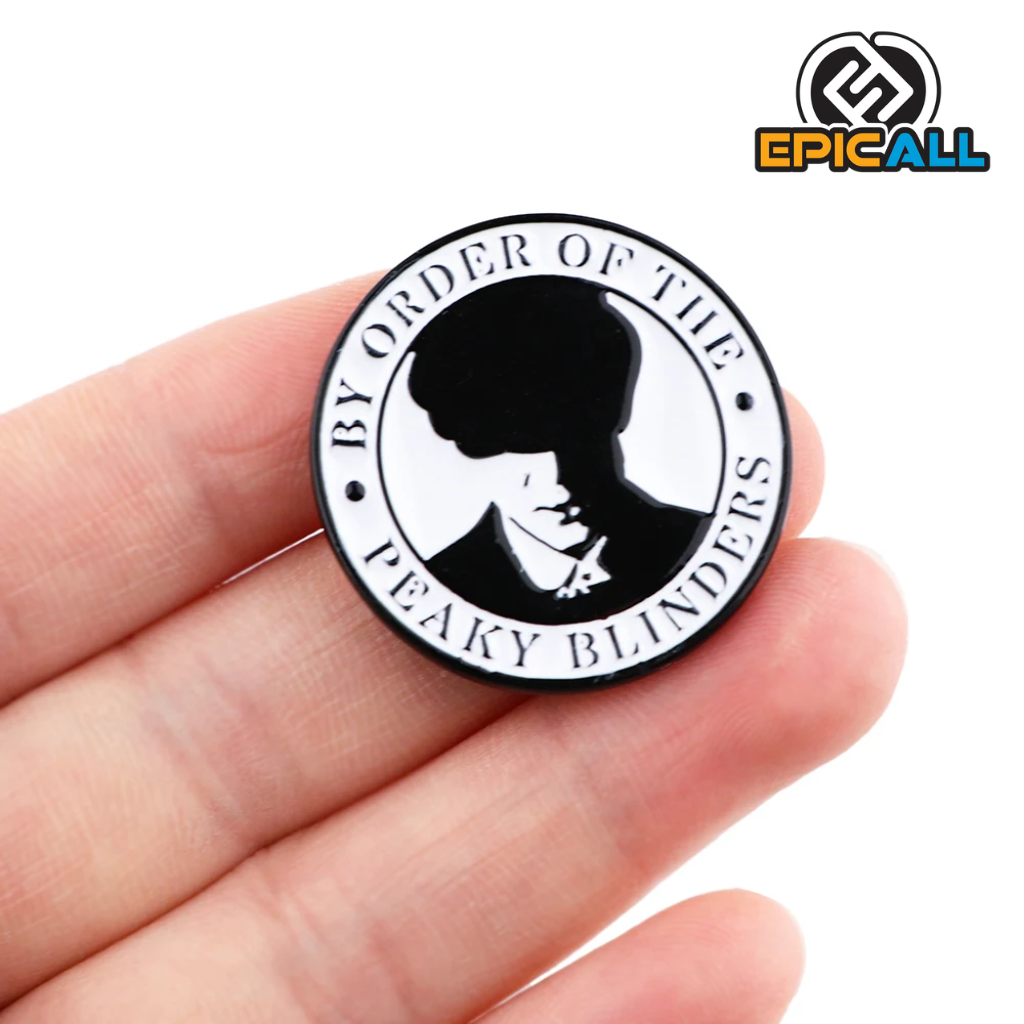 La imagen muestra un pin metálico redondo con un diseño en blanco y negro que incluye la silueta de un personaje de Peaky Blinders y la frase "By order of the Peaky Blinders". El pin mide 3 cm de diámetro.