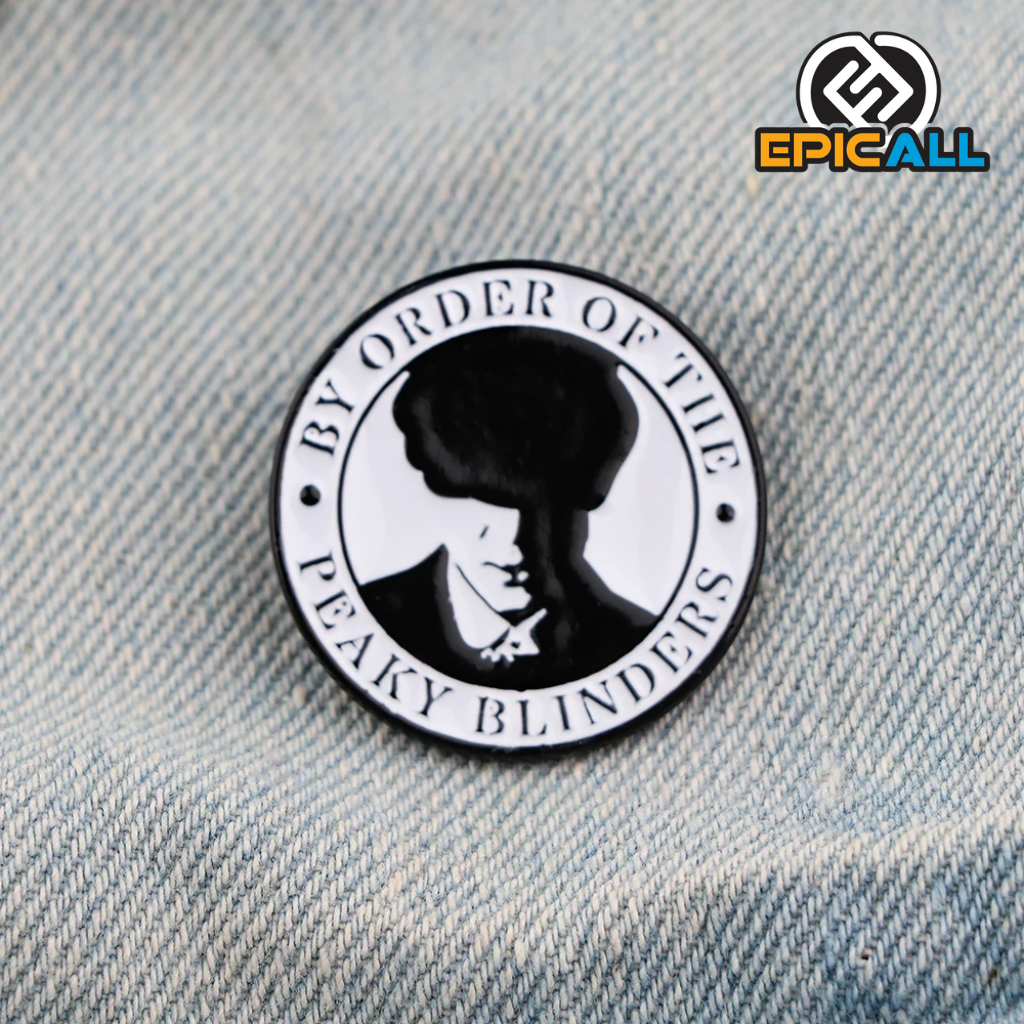 La imagen muestra un pin metálico redondo con un diseño en blanco y negro que incluye la silueta de un personaje de Peaky Blinders y la frase "By order of the Peaky Blinders". El pin mide 3 cm de diámetro.