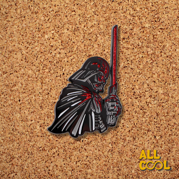 La imagen muestra un pin metálico de Darth Vader con un sable láser rojo, de 4.5 cm de alto y 2.5 cm de ancho.