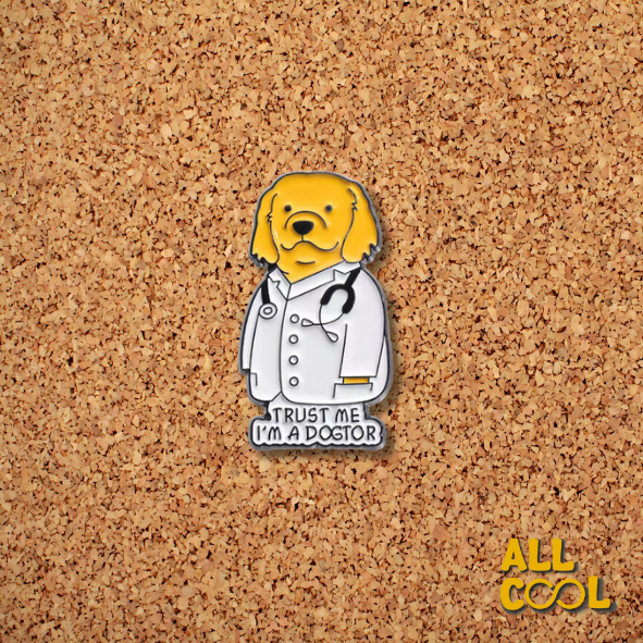 Imagen de un pin metálico con un perro con bata de doctor y la frase “Trust Me I’m Dogtor”. El pin mide 3 cm de alto y 2.5 cm de ancho.