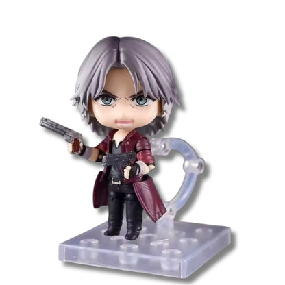 Figura articulada coleccionable tipo Nendoroid de 10 cm de altura de Dante de Devil May Cry, luciendo abrigo rojo, cabello plateado, sosteniendo sus pistolas gemelas Ebony e Ivory y posando sobre una base transparente con soporte.