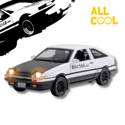 Un auto coleccionable a escala 1/32 del Toyota AE86 Sprinter Trueno, el coche icónico de Takumi Fujiwara en Initial D. El auto es de color blanco y negro con detalles en otros colores. Tiene un diseño detallado y un acabado brillante.