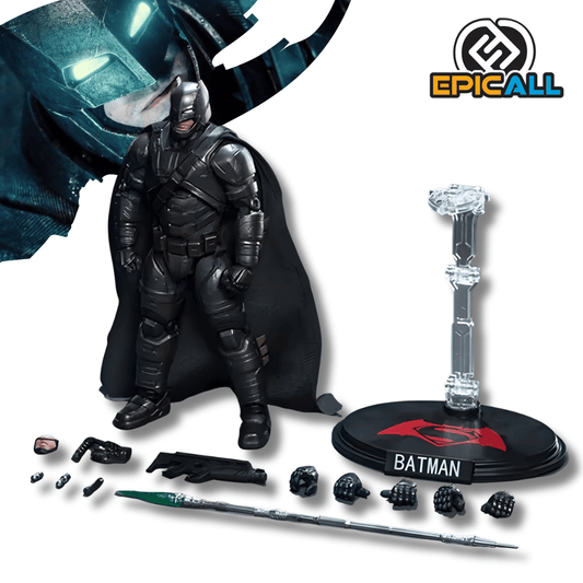 Una figura de acción articulada de Batman con Armadura, de color negro o gris oscuro, de unos 18 cm de alto. El personaje está de pie, y junto a él se exhiben diversos accesorios, incluyendo manos intercambiables, una lanza verde, una pistola y una base de exhibición redonda y negra con el símbolo de Superman.