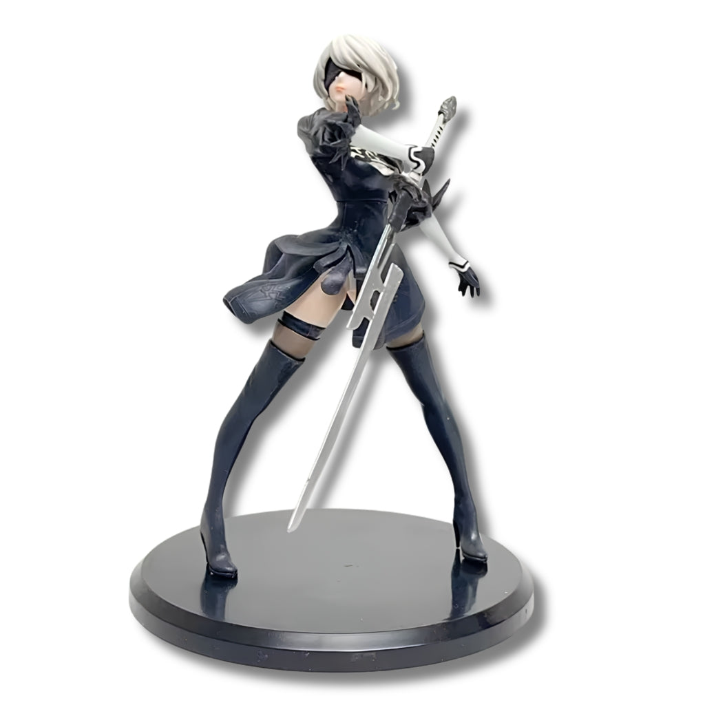 Figura coleccionable de PVC de 13 cm de altura de la androide 2B de NieR Automata en pose de combate dinámica, luciendo vestimenta gótica negra con bordados, visor visor de combate ciego, cabello corto platinado y sosteniendo su espada katana sobre una base circular negra.