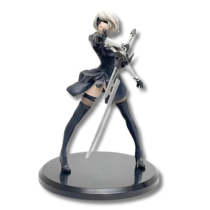 Figura coleccionable de PVC de 13 cm de altura de la androide 2B de NieR Automata en pose de combate dinámica, luciendo vestimenta gótica negra con bordados, visor visor de combate ciego, cabello corto platinado y sosteniendo su espada katana sobre una base circular negra.
