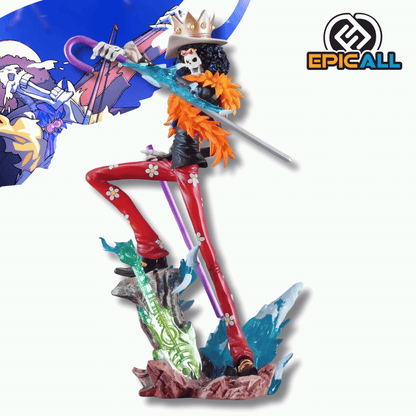 Una figura de estatua de Brook, el personaje esqueleto de One Piece, de unos 33 cm. La figura viste un traje de rayas rojas con flores blancas, una chaqueta negra y una bufanda grande de plumas naranjas. Sostiene una espada plateada y un bastón morado, y está de pie sobre una base marrón con detalles de hielo azul y una guitarra verde.