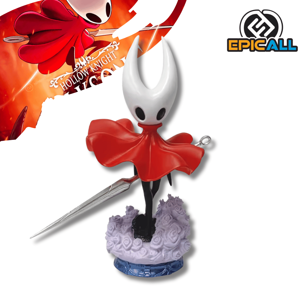 Una figura de estatua del personaje Hornet del videojuego Hollow Knight, de unos 19 cm de altura. El personaje es negro con una máscara blanca con cuernos y una capa roja. Sostiene una aguja larga y delgada, y está de pie sobre una base que simula un terreno con pequeñas flores moradas.