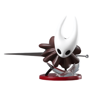 Una figura de estatua de Hornet del videojuego Hollow Knight, de unos 11.5 cm. El personaje tiene una máscara blanca con cuernos, un cuerpo pequeño de color marrón oscuro (o rojo), y sostiene una aguja delgada. La figura está montada sobre una pequeña base roja con un efecto de ataque translúcido que simula movimiento.