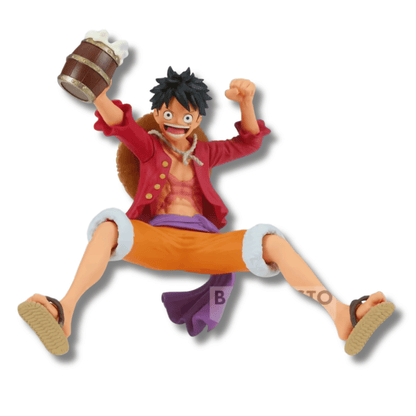 Estatua de Monkey D. Luffy de One Piece saltando con un tarro de bebida en un banquete pirata. El personaje viste su camisa roja abierta, pantalones naranjas y lleva su sombrero de paja a la espalda.