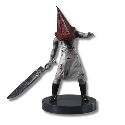 Figura de estatua de Pyramid Head de 18 cm sobre un fondo neutro. El personaje viste un delantal largo de color beige sucio y ensangrentado, tiene los brazos musculosos y desnudos, y porta su icónico casco piramidal metálico y oxidado. Con su mano derecha sujeta un enorme cuchillo metálico desgastado que descansa sobre el suelo. La pose es encorvada y amenazante.