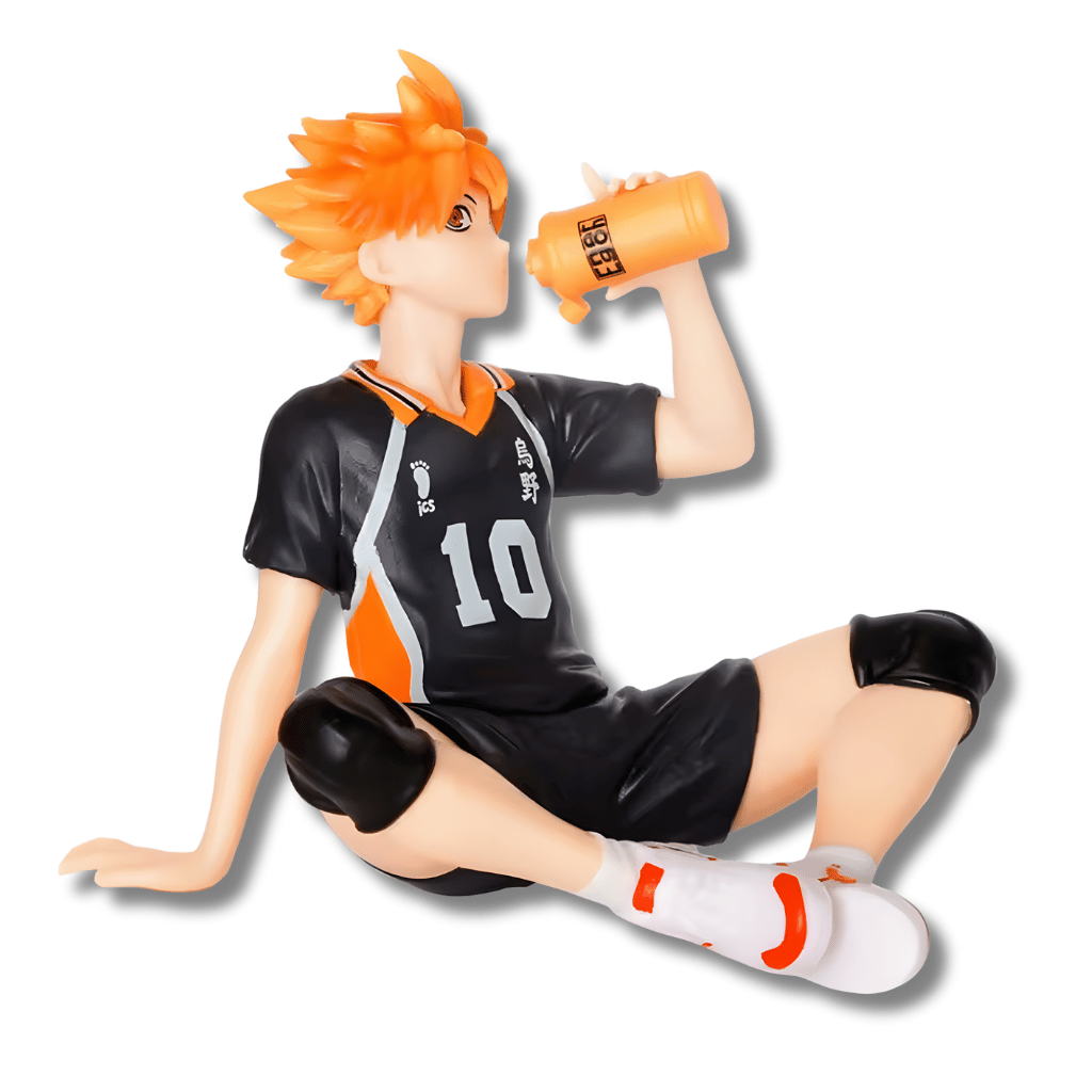 Figura de colección de Shoyo Hinata del anime Haikyuu!! de 10 cm. El personaje aparece sentado con una expresión alegre, vistiendo el uniforme de voleibol negro y naranja del Karasuno con el número 10. Su distintivo cabello naranja está detallado con puntas hacia arriba. La figura está diseñada para apoyarse en superficies planas.
