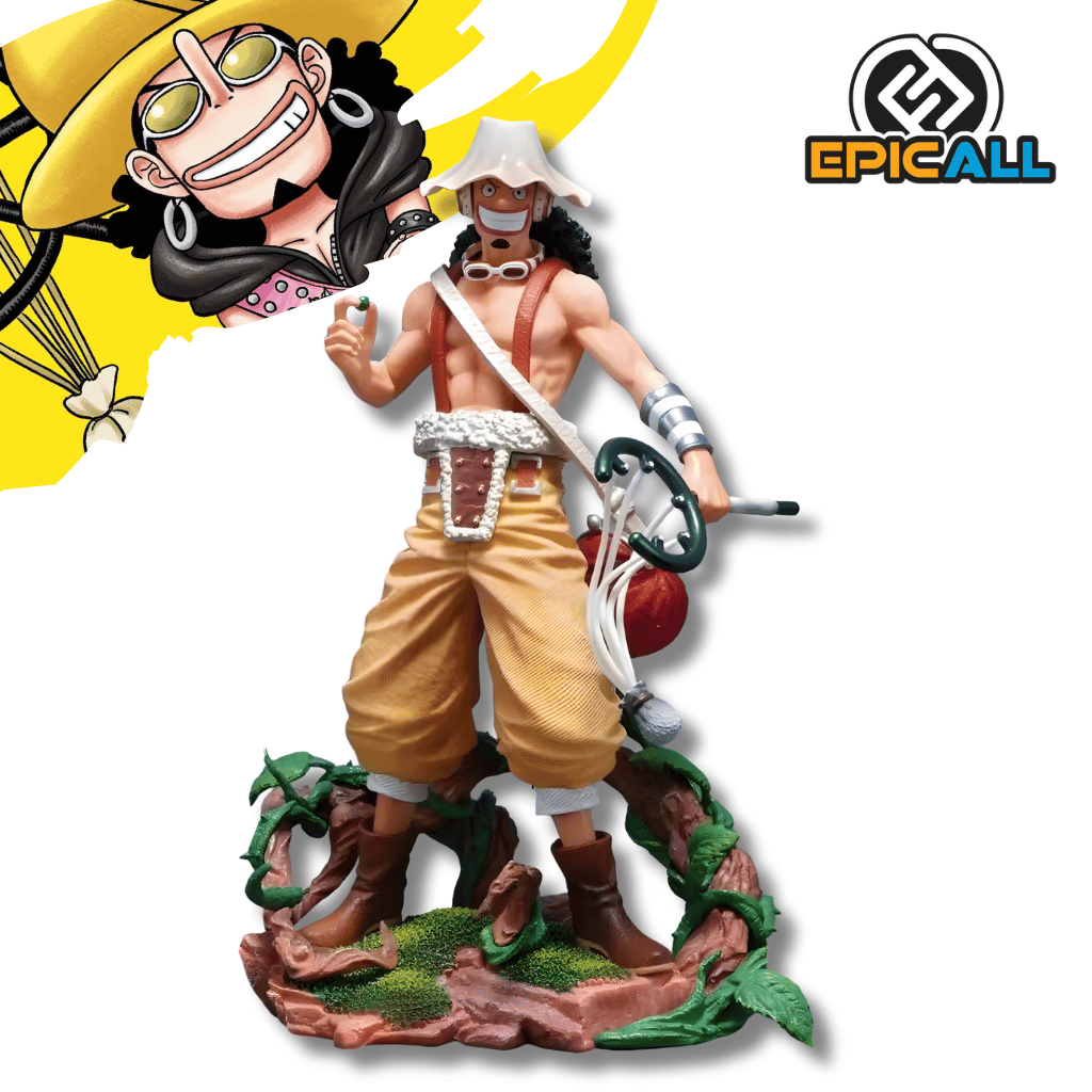 Una figura de estatua de Usopp del anime One Piece, de unos 25 cm de altura. El personaje está de pie sobre una base marrón con vegetación, vistiendo pantalones holgados de color canela y un arnés. Lleva su sombrero blanco y redondo, gafas y tiene su tirachinas grande colgado a un lado.