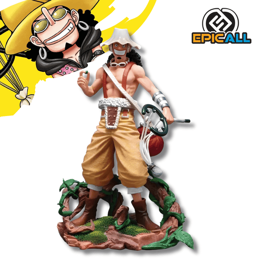 Una figura de estatua de Usopp del anime One Piece, de unos 25 cm de altura. El personaje está de pie sobre una base marrón con vegetación, vistiendo pantalones holgados de color canela y un arnés. Lleva su sombrero blanco y redondo, gafas y tiene su tirachinas grande colgado a un lado.