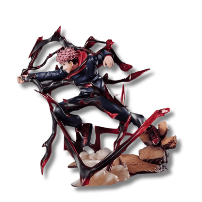 Una figura de estatua del personaje Yuji Itadori de Jujutsu Kaisen, de unos 19 cm de altura. Viste un traje oscuro con detalles rojos y está representado en una pose de acción, saltando o cargando un golpe. La figura está rodeada por grandes efectos de aura o energía de color negro y rojo, y se apoya sobre una base de rocas.