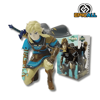 Figura de colección de Link del videojuego The Legend of Zelda: Tears of the Kingdom de 12 cm de altura. El héroe aparece en una pose arrodillada sobre una pierna, vistiendo su túnica azul con detalles marrones y una capa oscura ondeante detrás. Su brazo derecho muestra grabados de color turquesa, y en su espalda se asoma la empuñadura de su espada. La figura tiene un acabado detallado en el cabello rubio y los rasgos del rostro.