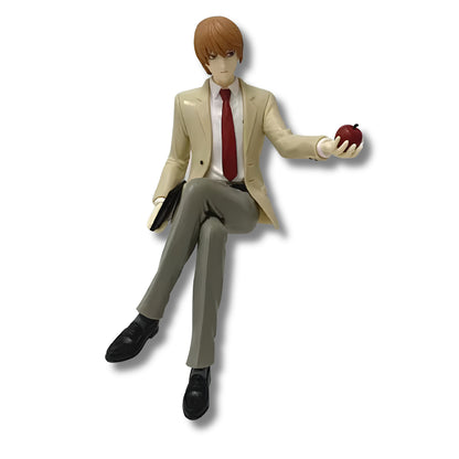Figura coleccionable de PVC de 16 cm de altura de Light Yagami de Death Note en pose sentada de borde o topper, vistiendo traje formal beige con corbata roja, sosteniendo la Death Note negra en la mano derecha y extendiendo una manzana roja en la palma izquierda.