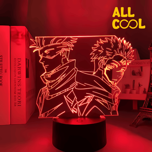 Una lámpara LED con diseño 3D de Satoru Gojo y Sukuna, dos personajes del anime Jujutsu Kaisen. La imagen muestra a ambos personajes en una pose de combate, con un fondo oscuro. La lámpara tiene una base circular y emite una luz suave.