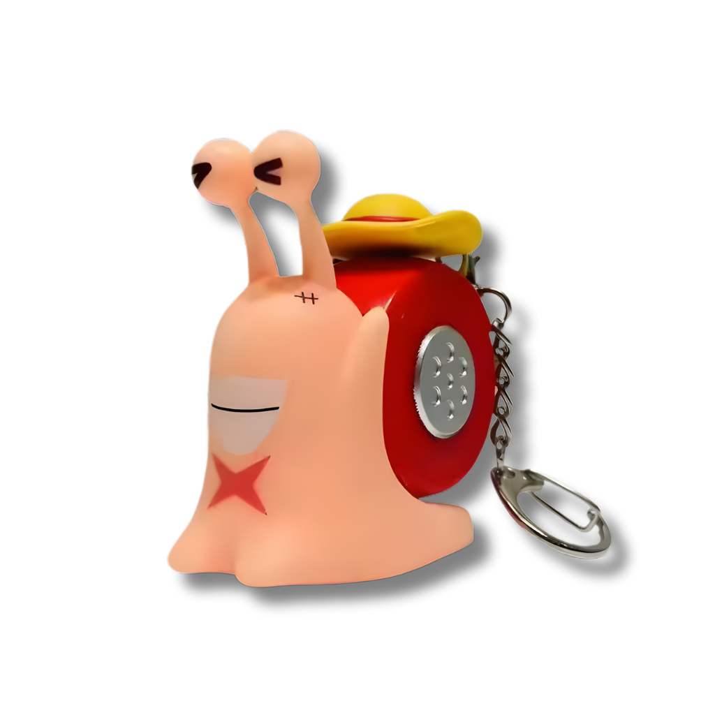 Un llavero con una figura de un Den Den Mushi (caracol telefónico) del anime One Piece. La figura es de color rosa pálido, tiene un caparazón rojo con detalles plateados y lleva un pequeño sombrero de paja amarillo y rojo. La figura tiene una cicatriz en forma de X en su mejilla izquierda y un aro de metal para llaves.