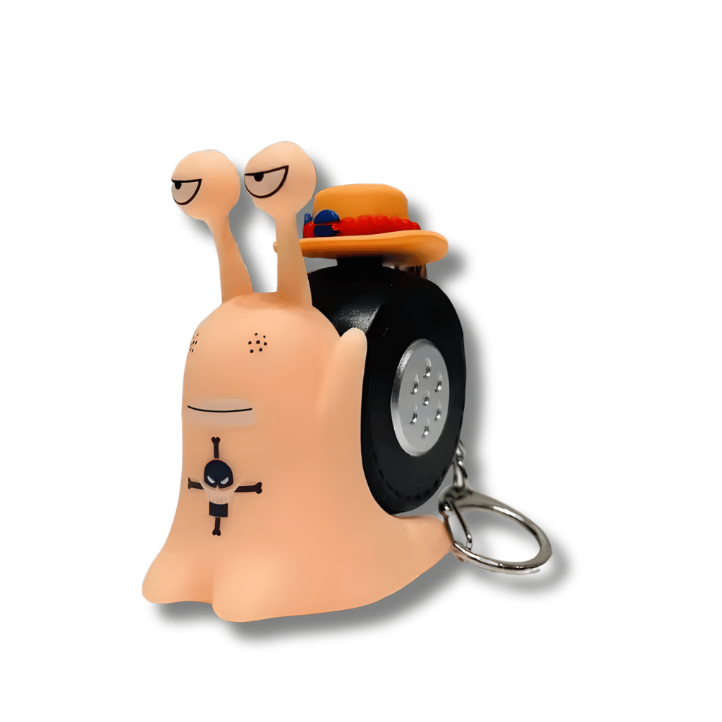Un llavero con una figura de un Den Den Mushi (caracol telefónico) del anime One Piece. La figura es de color rosa pálido, tiene un caparazón negro que parece una rueda y lleva un pequeño sombrero naranja con cuentas rojas. El rostro del Den Den Mushi tiene la marca del tatuaje de Ace y un aro de metal para llaves.