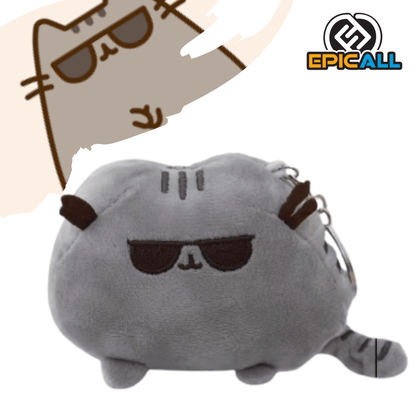 Llavero de peluche suave de Pusheen el gato en color gris con gafas de sol oscuras bordadas, orejas y cola a rayas, con argolla metálica en la parte posterior sobre fondo blanco.